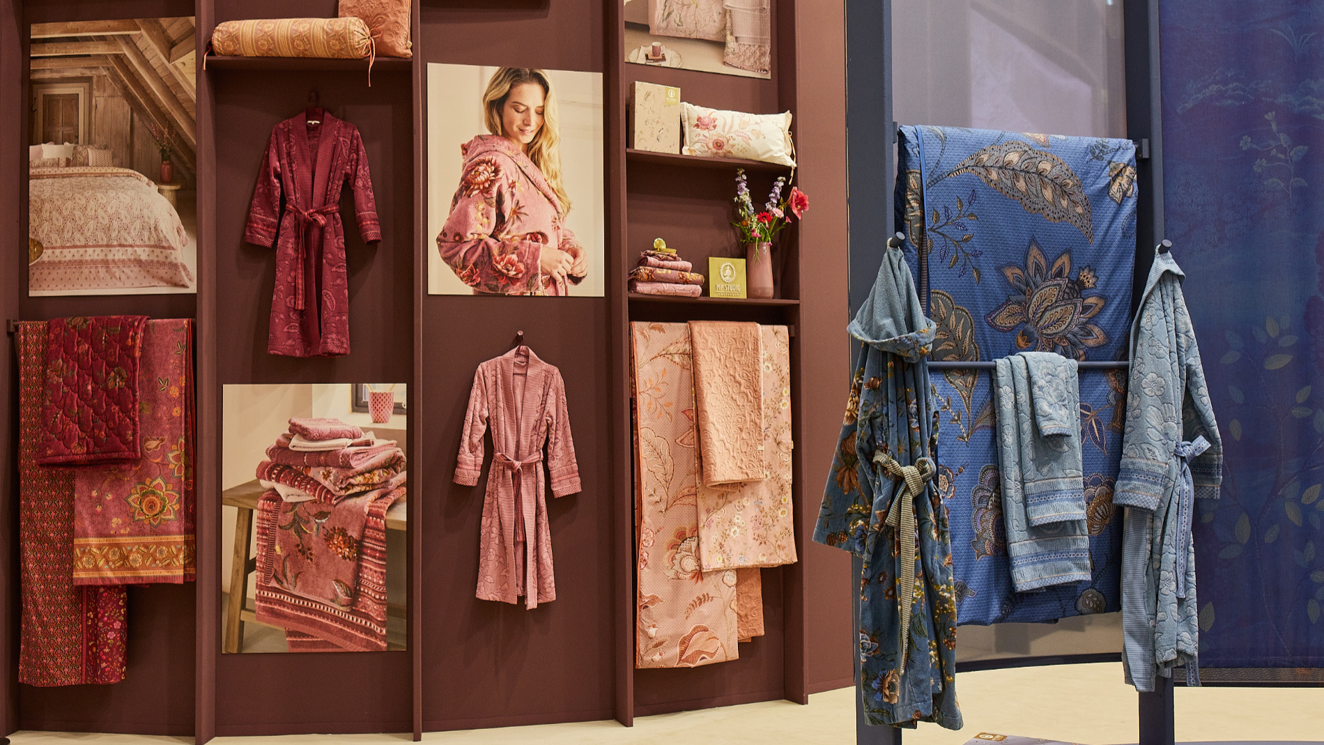 Display of home textiles such as bathrobes, towels, and fabrics in warm tones at a decorative exhibition stand